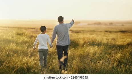 This Will All Be Yours, Son. Shot Of A Man Taking His Son For A Walk Out On An Open Field.