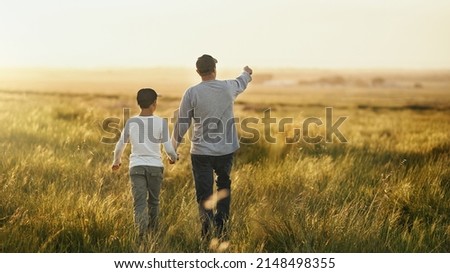 This will all be yours, son. Shot of a man taking his son for a walk out on an open field.