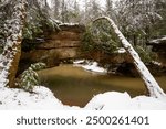 This is a winter, snowy scene of Rock Bridge Arch and Swift Camp Creek within Kentucky