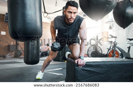 This is your daily reminder to train like a beast. Shot of a sporty young man exercising with a dumbbell in a gym.