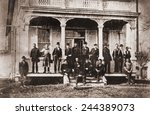 Thomas Edison with the engineers and technicians of his Menlo Mark workshop. Edison is under the central arch, leaning against the support with his hands in his pockets. Ca. 1880.