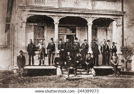 Thomas Edison with the engineers and technicians of his Menlo Mark workshop. Edison is under the central arch, leaning against the support with his hands in his pockets. Ca. 1880.