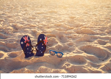 Thongs and sunglasses in sand on a beach, Australia day concept