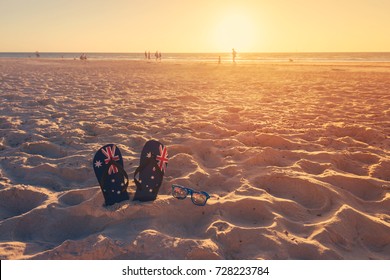 Thongs and sunglasses in sand on a beach, Australia day concept