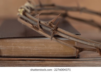 Thorn crown on closed holy bible book with golden pages. A close-up. Jesus Christ's love, sacrifice, crucifixion, salvation, and forgiveness. Christian biblical concept. Selective focus. - Shutterstock ID 2276004371