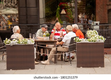 Thorn/Torun/Poland-July 2020:A Group Of Male Senior Friends At Outdoor Sitting Of A Restaurant, Drinking, Talking, Smiling, Joking At The Old Town Market During Pandemic Of Coronavirus. Selected Focus