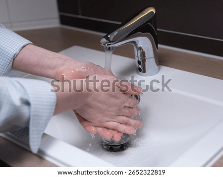 Thorough hand cleaning under sensor-activated faucet showing proper hygiene practices in modern washroom