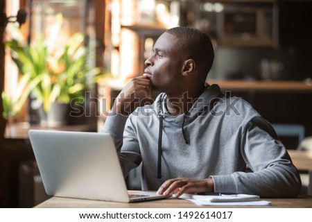 Thoughtful african american businessman lost in thoughts search for inspiration sit at cafe table using laptop, dreamy pensive contemplative black student looking away thinking of new creative ideas