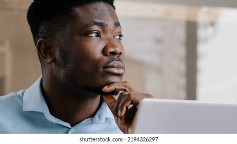 Thoughtful african american businessman writer dreamer genius man biracial guy holds hand on chin creates business plan come up with idea for startup uses computer typing text creates internet - Shutterstock ID 2194326297
