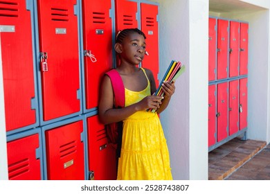 Thoughtful african american schoolgirl with books leaning on locker at school corridor. Education, childhood, development, learning and school, unaltered. - Powered by Shutterstock