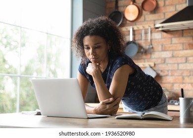 Thoughtful African American Woman Stand By Work Desk At Home Office Look At Laptop Screen Create New Decision Consider Idea. Young Black Woman Freelancer Student Focused On Computer Think On Research