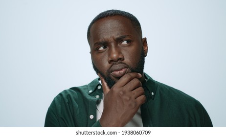 Thoughtful african man thinking indoors. Afro surprised student looking camera. African american doubtful guy getting idea at white background. Shocked male person pointing finger in studio. - Powered by Shutterstock