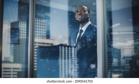 Thoughtful African-American Businessman in a Perfect Tailored Suit Standing in His Office Looking out of the Window on Big City. Successful Investment Manager Planning Strategy. Outside Shot - Powered by Shutterstock