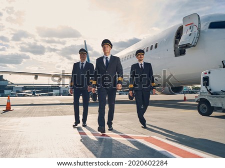 Thoughtful airman surrounded by his two colleagues going along the runway