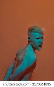 Thoughtful Albino Caucasian Guy Posing And Looking Away. Young Modern Bearded Blonde Man Of Generation Z With Naked Torso. Isolated On Orange Background. Studio Shoot. Copy Space