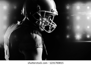 Thoughtful American football player in helmet standing against black background - Powered by Shutterstock