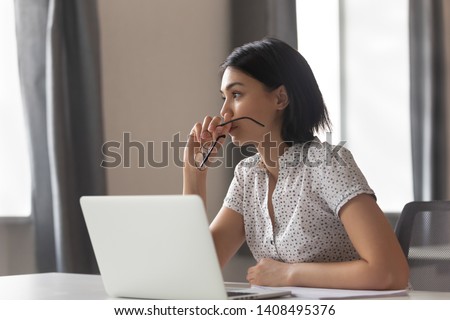 Thoughtful anxious asian business woman looking away thinking solving problem at work, worried serious young chinese woman concerned make difficult decision lost in thought reflecting sit with laptop
