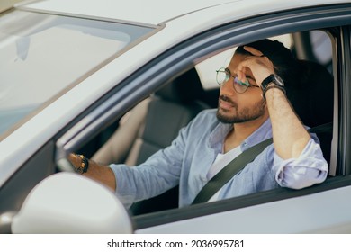 Thoughtful arab guy driving nice car, dreaming about something while stuck in traffic, pensive middle-eastern guy driver with fasten seat belt looking at road, leaning on his hand, copy space