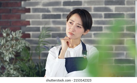 Thoughtful Asian Female Shop Clerk. Restaurant. Flower Shop.