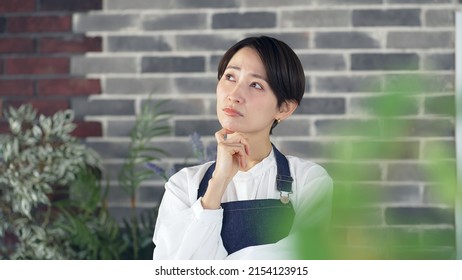 Thoughtful Asian Female Shop Clerk. Restaurant. Flower Shop.