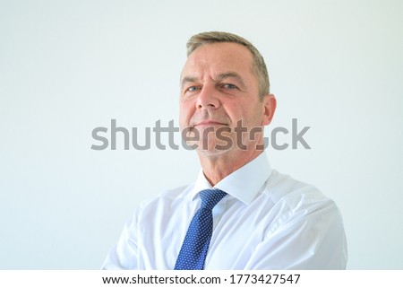 Thoughtful authoritative businessman portrait on white scrutinising the camera with an assessing astute expression