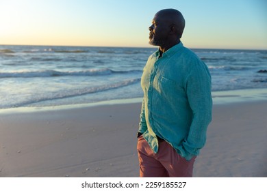 Thoughtful bald african american senior man with hands in pockets looking at sea against sky at dusk. Copy space, beach, retirement, scenic, unaltered, lifestyle, vacation, enjoyment and nature. - Powered by Shutterstock