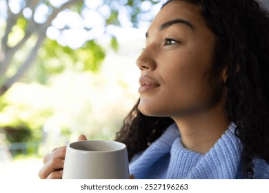 Thoughtful biracial woman holding cup of coffee and looking out window at home. Lifestyle, free time and domestic life, unaltered. - Powered by Shutterstock