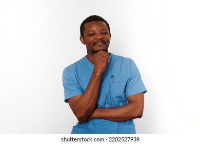 Thoughtful Black Surgeon Doctor Bearded Man In Blue Coat Isolated On White Background. Brooding Adult Black African American Practicing Surgeon Portrait, Pensive Look