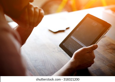 Thoughtful Business Man Looking To The Digital Tablet Screen While Sitting In Modern Loft Interior At Wooden Table,entrepreneur Or Freelancer Work On Touchscreen Pad At The Office,flare Sun And Filter