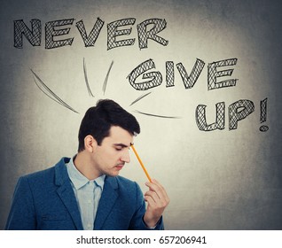 Thoughtful businessman holding pencil pointed to face  drawing text over head  Never give up  positive thinking concept isolated grey wall background 