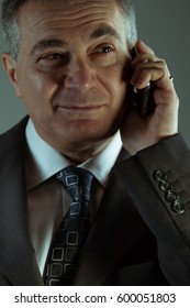 Thoughtful Businessman Listening To A Telephone Conversation On A Land Line Phone, Close Up View Of His Face