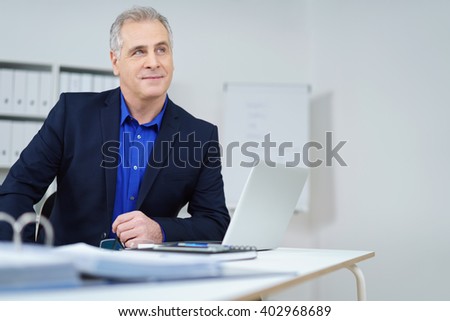 Thoughtful businessman seeking a solution to a problem or planning a strategy as he sits at his desk looking up into the air