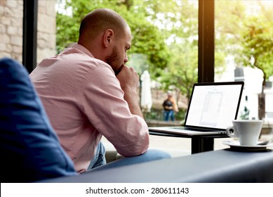 Thoughtful businessman sitting front open laptop computer on sofa of luxury hotel interior, worried freelancer working on notebook in modern cafe, entrepreneur at coffee break preparing for meeting - Powered by Shutterstock