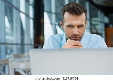 Thoughtful Businessman Working On Laptop At Modern Office