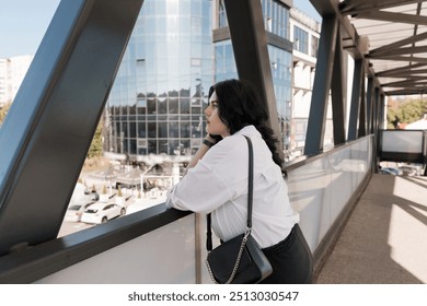 Thoughtful Businesswoman Contemplating Urban Cityscape from Modern Pedestrian Bridge. - Powered by Shutterstock