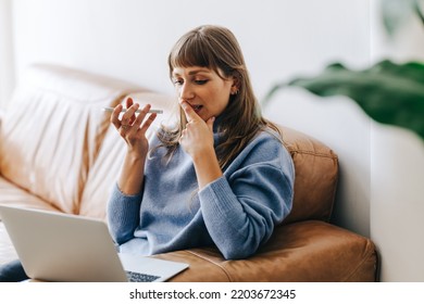 Thoughtful Businesswoman Having A Phone Call Discussion While Sitting In An Office Lobby. Female Entrepreneur Looking At A Laptop Screen While Speaking On The Phone In A Modern Workplace.