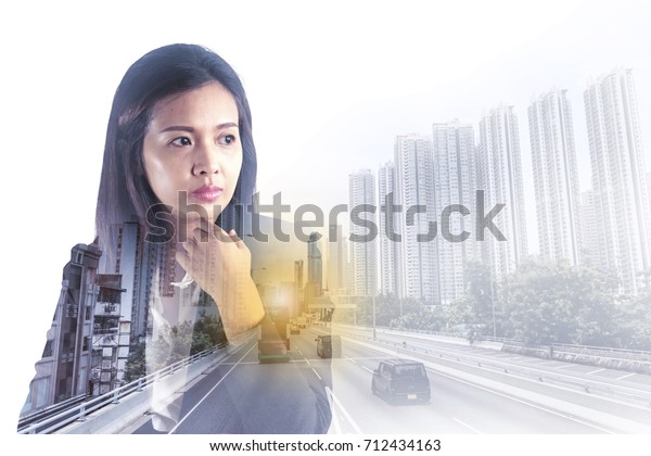 Thoughtful businesswoman with looking far away\
on city background. Double\
exposure.