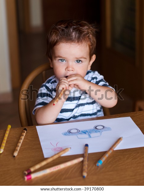 Thoughtful child\
with pencils and a car\
drawing