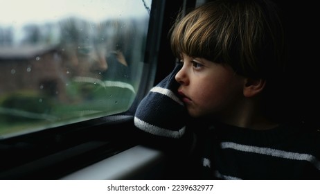 Thoughtful child staring at train window feeling sadness. Pensive passenger boy traveling in modern transportation during gray moody day - Powered by Shutterstock