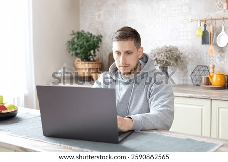 Thoughtful concentrated guy freelancer using computer, watching webinar, remote working in home office analyzing online data market thinking doing web research looking at laptop sit at kitchen desk