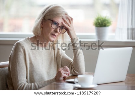 Thoughtful confused mature business woman concerned thinking about online problem looking at laptop, frustrated worried senior middle aged female reading bad email news, suffering from memory loss 商業照片 © 