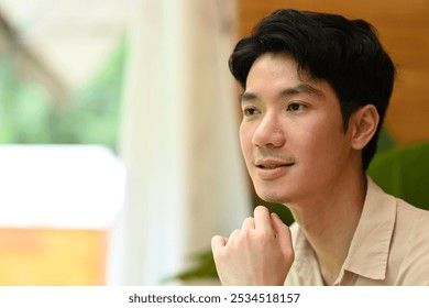 Thoughtful Contemplation in a Relaxed Space, A man gazes thoughtfully into the distance, resting his chin on his hand. The soft lighting and blurred background of nature. - Powered by Shutterstock