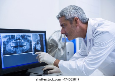 Thoughtful dentist examining an x-ray on the monitor in clinic