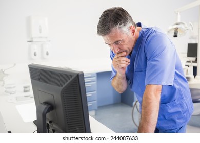 Thoughtful Dentist Using Computer In Dental Clinic