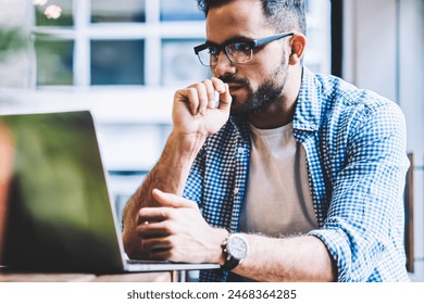 Thoughtful it developer thinking about fixing software bugs on netbook downloading files from network,contemplative male student watching tutorial on web site learning online via laptop computer