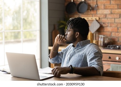 Thoughtful distance employee looking at window in deep thought, working from home, sitting at kitchen table with laptop, pondering on future career vision. Remote student thinking over learning task. - Powered by Shutterstock