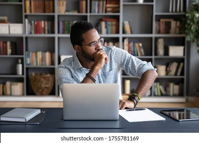 Thoughtful Doubtful African Businessman In Tension Sitting At Workplace Desk Near Laptop Distracted From Work Makes Difficult Decision Looking At Window Feels Uncertain Thinking Over Problem Solution