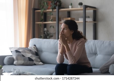 Thoughtful Doubtful Young Woman Sitting Alone On Couch, Feeling Nervous About Hard Decision. Stressed Millennial Girl Thinking Of Loneliness Psychological Problem, Regret About Relationship Mistake.