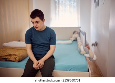 Thoughtful Down Syndrome Man Sitting Alone In His Bedroom.