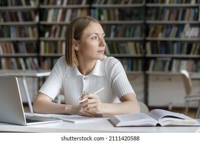 Thoughtful dreamy pretty student girl working on essay, study project in library, writing notes at laptop, looking away in deep thoughts, thinking over creative ideas for research - Powered by Shutterstock